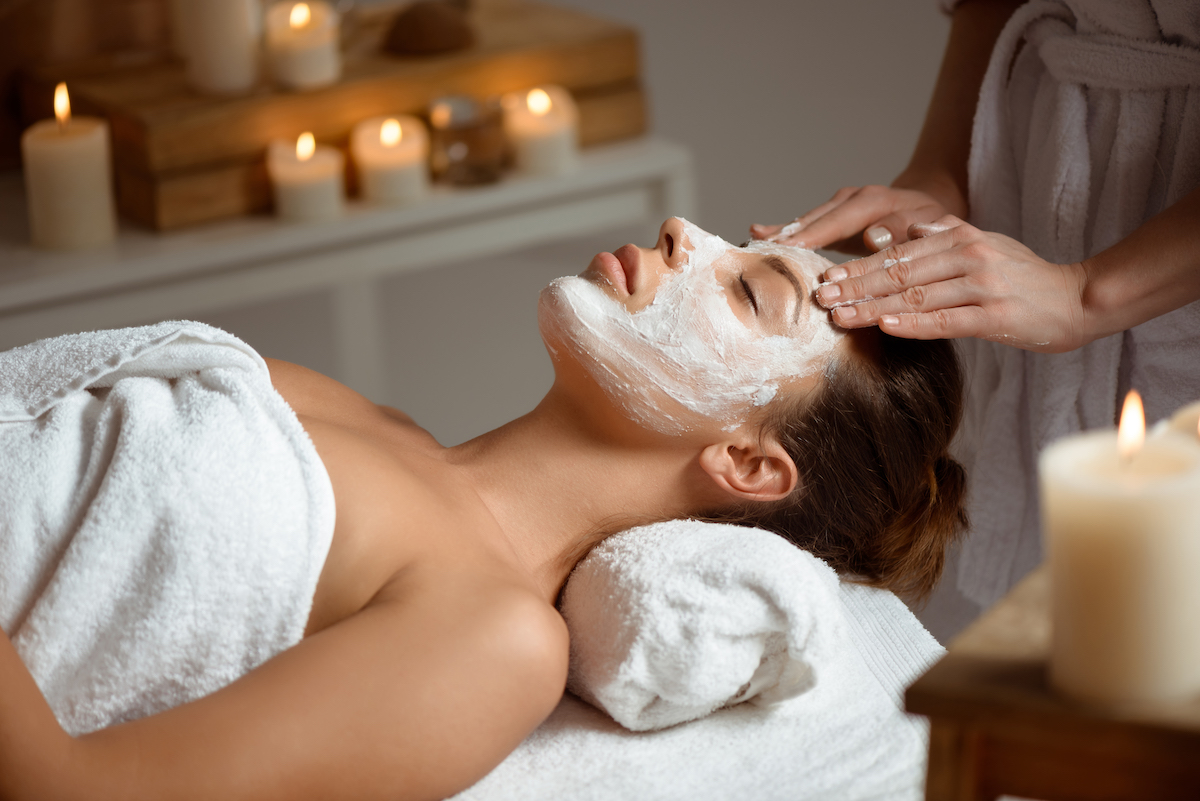 Young beautiful brunette girl in mask for face relaxing in spa salon. Eyes closed. Copy space.